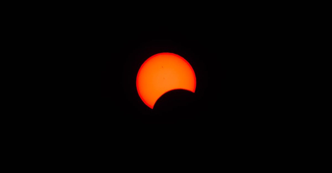 Stunning view of a partial solar eclipse with vibrant red hues in the sky, capturing nature's beauty.