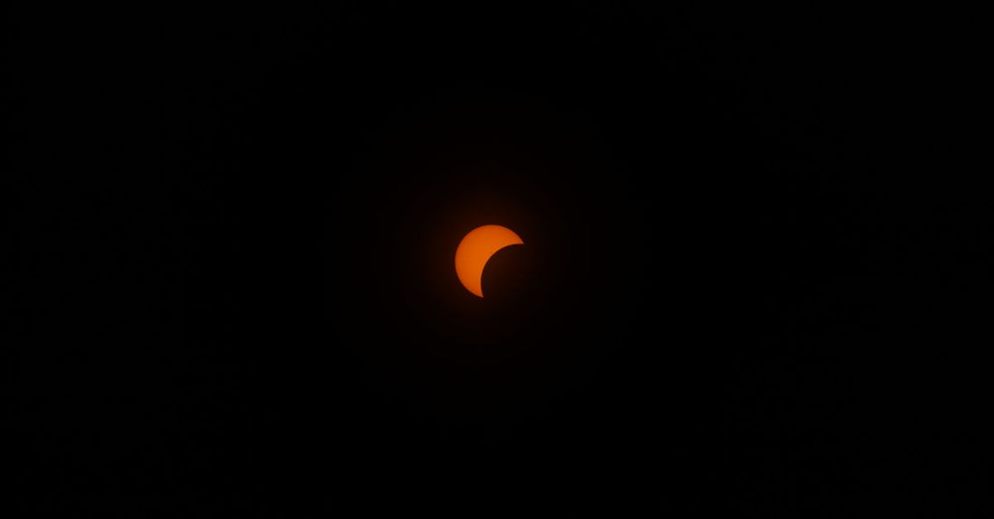 A striking partial solar eclipse in a dark sky, highlighting the sun's crescent shape.