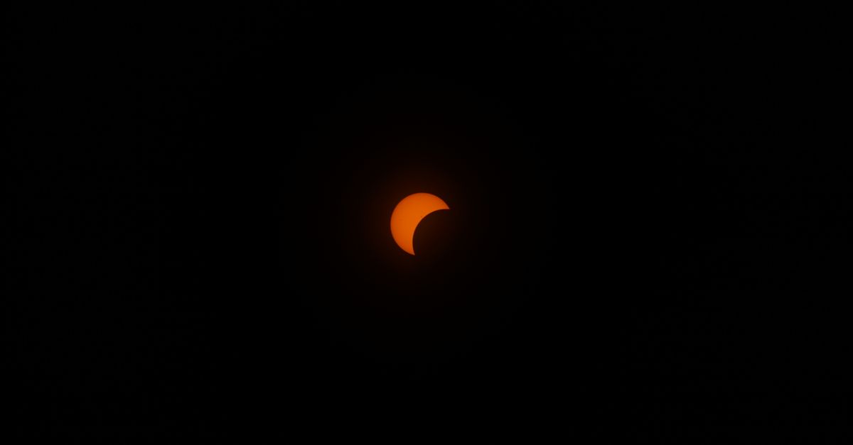 A striking partial solar eclipse in a dark sky, highlighting the sun's crescent shape.