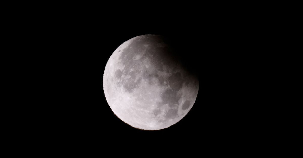 A captivating photo of a partial lunar eclipse set against a dark, starless night sky.